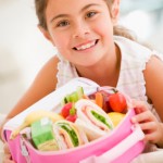 Young girl holding packed lunch in living room smiling